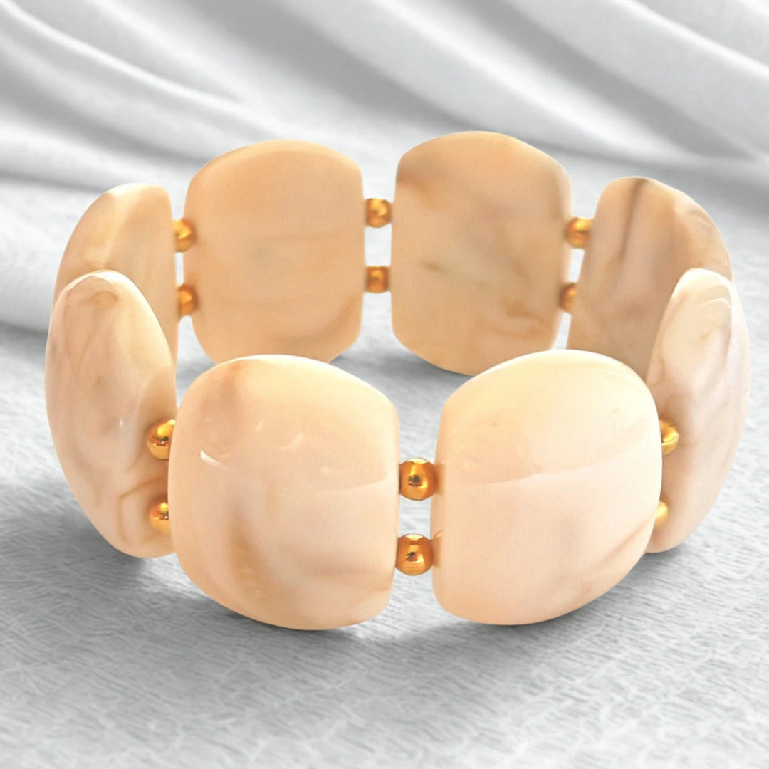Sublimez votre poignet avec ce bracelet large en résine effet pierre naturelle, rehaussé de perles dorées en acier inoxydable. Ses reflets profonds et sa texture lumineuse en font un bijou tendance, parfait pour habiller vos tenues d’une touche chic et contemporaine.