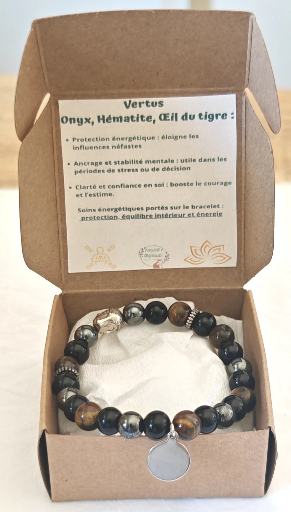 Bracelet en pierres naturelles (Onyx, Hématite, Œil du tigre) monté sur élastique, avec médaillon personnalisable. Apporte protection, ancrage et confiance en soi. Il est personnalisable avec son pendentif à graver