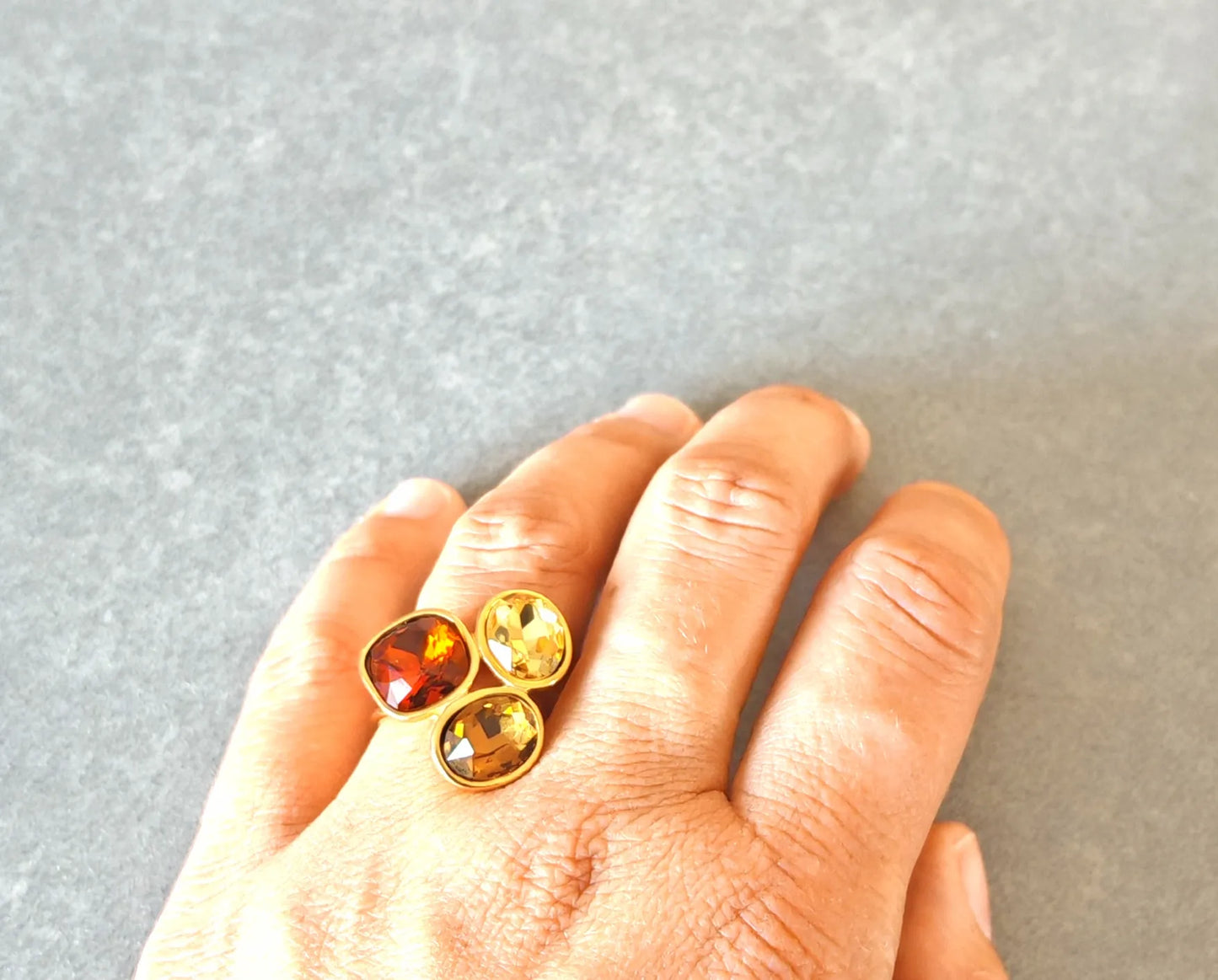 Rayonnez d'élégance avec cette bague dorée ornée de trois pierres facettées aux reflets chauds. Entre nuances ambrées, dorées et orangées, ce bijou capte la lumière à chaque mouvement et habille la main d'un éclat luxueux.