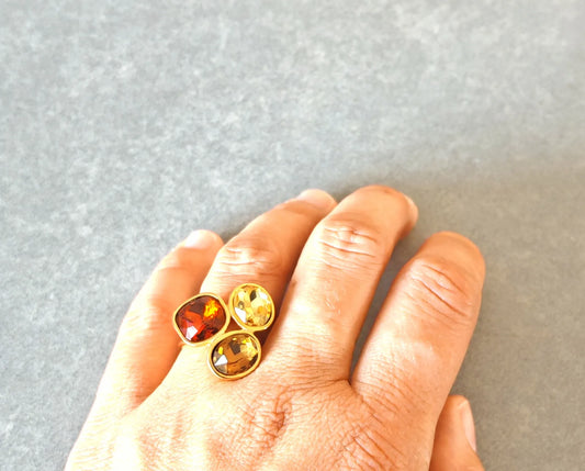 Rayonnez d'élégance avec cette bague dorée ornée de trois pierres facettées aux reflets chauds. Entre nuances ambrées, dorées et orangées, ce bijou capte la lumière à chaque mouvement et habille la main d'un éclat luxueux.