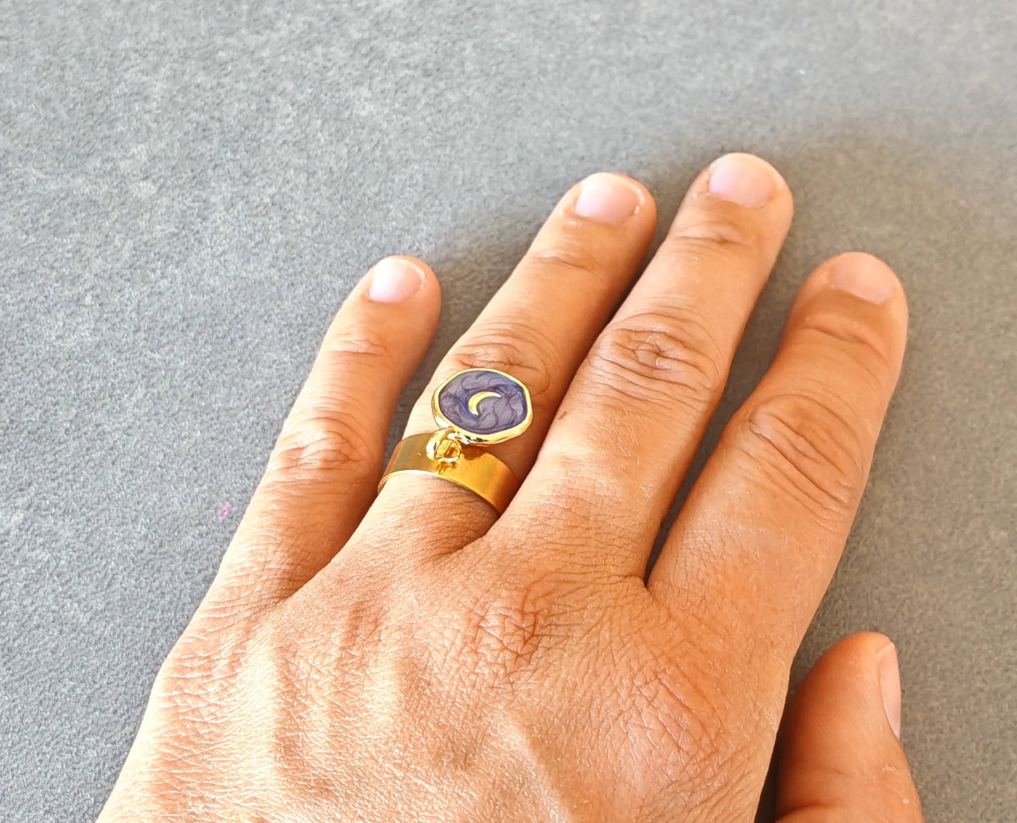 Laissez-vous séduire par cette bague dorée ornée d’un pendentif rond émaillé violet et d’un motif lune dorée. Elle incarne la féminité, la douceur et la magie du ciel nocturne. Son design raffiné et symbolique en fait un bijou plein de charme et d’énergie positive.