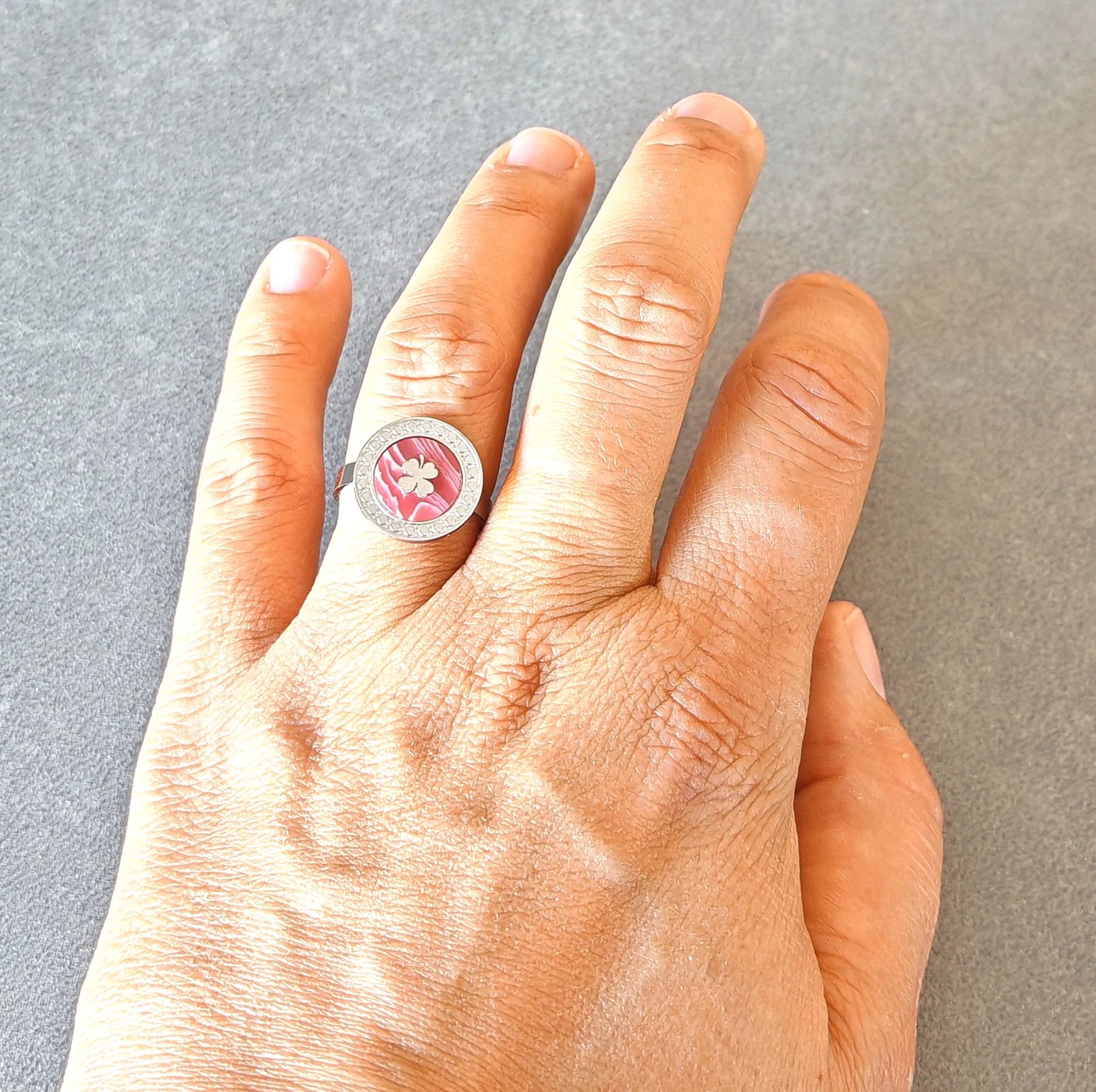 Portez la chance à votre doigt avec cette bague argentée au design raffiné. Son médaillon rond révèle un fond nacré rose doux, orné d’un trèfle délicat, symbole de chance et de positivité. Un bijou à la fois élégant et plein de sens, idéal pour illuminer vos journées.