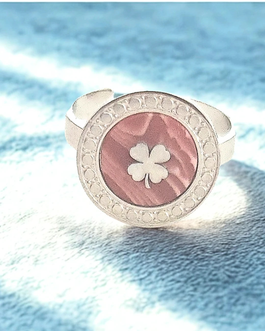 Portez la chance à votre doigt avec cette bague argentée au design raffiné. Son médaillon rond révèle un fond nacré rose doux, orné d’un trèfle délicat, symbole de chance et de positivité. Un bijou à la fois élégant et plein de sens, idéal pour illuminer vos journées.