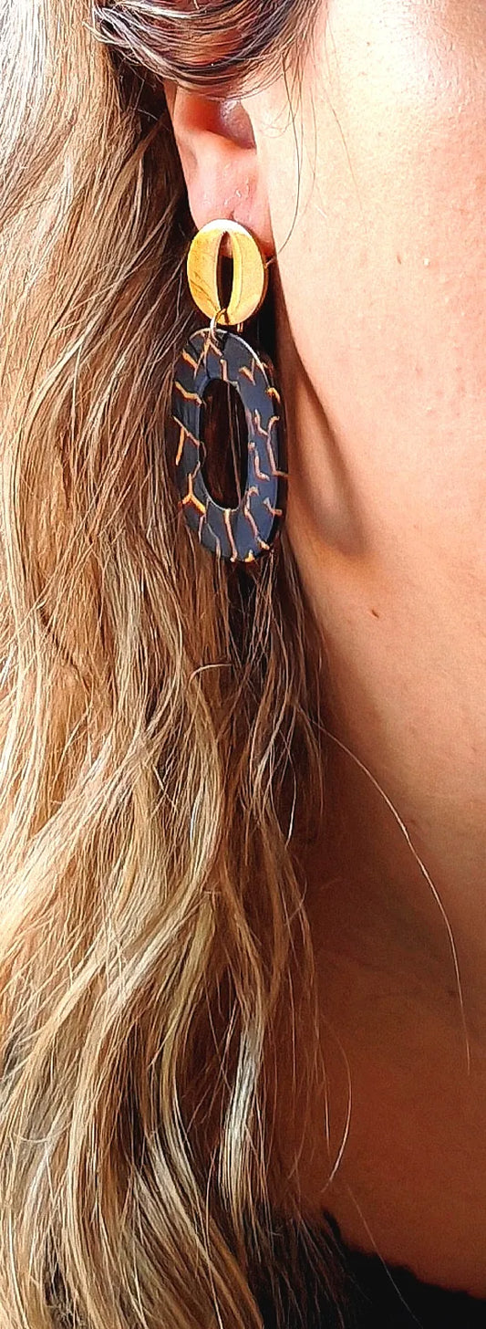Affirmez votre style avec ces boucles d'oreilles noires et dorées au design géométrique et raffiné. Leur contraste subtil entre l'effet marbré noir aux éclats dorés et la brillance du métal apporte une touche d'élégance contemporaine à toutes vos tenues.