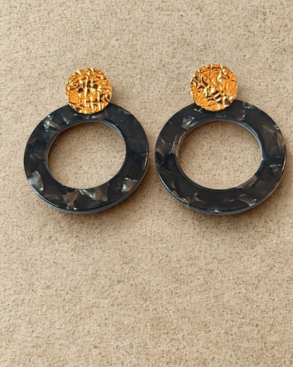 Boucles d’oreilles originales en acier inoxydable doré et anneau noir effet marbré. Tendance, légères et résistantes, idéales pour un look moderne.