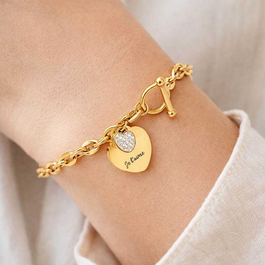 Ce bracelet en acier inoxydable est magnifiquement conçu avec une pampille en forme de cœur ornée d'un strass et une autre pampille pouvant être personnalisée selon vos envies.