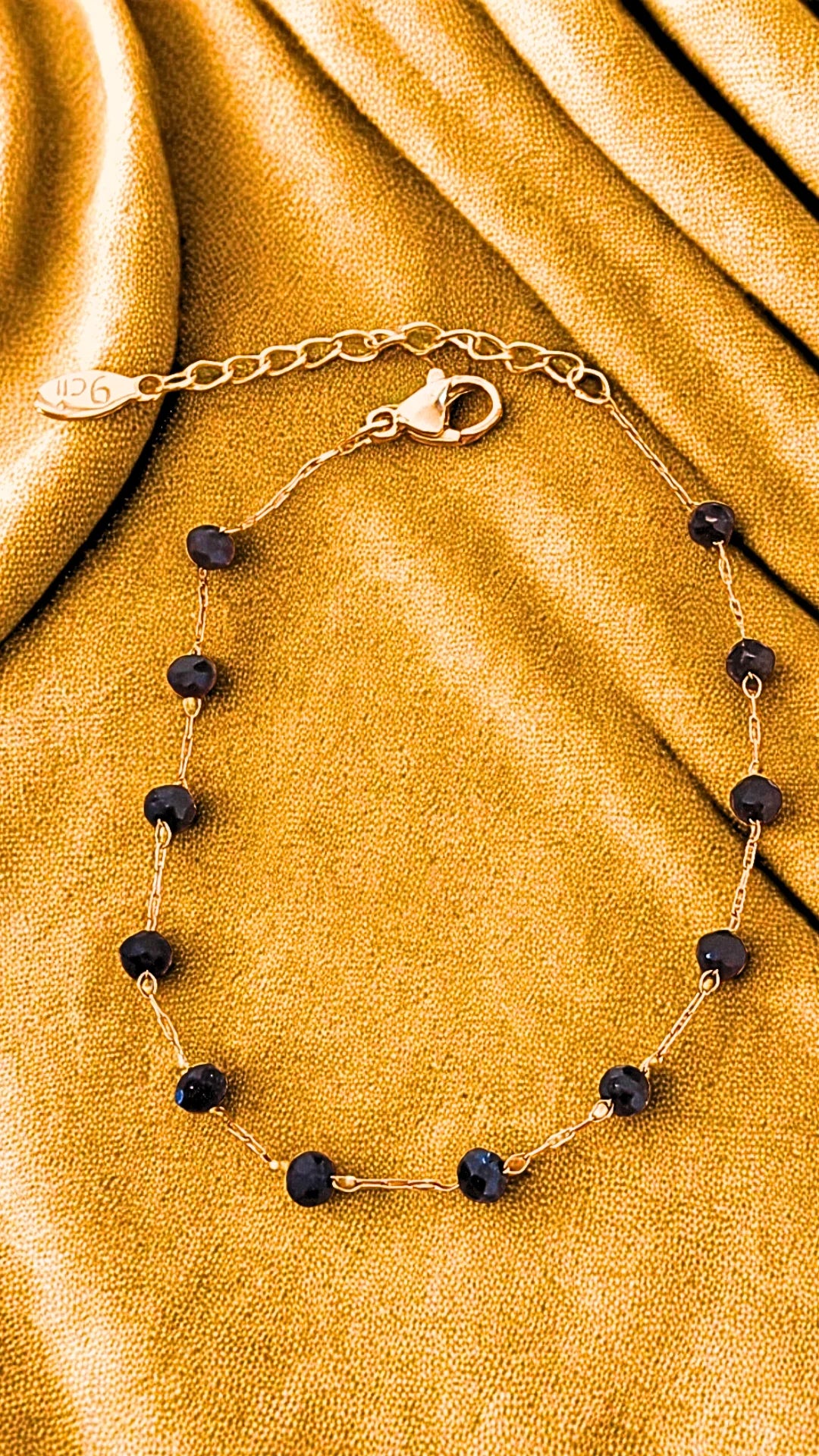 Bracelet fin en acier inoxydable doré orné de perles noires. Élégant, discret et résistant à l’eau, idéal pour un look raffiné au quotidien.