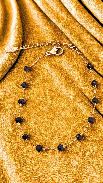 Bracelet fin en acier inoxydable doré orné de perles noires. Élégant, discret et résistant à l’eau, idéal pour un look raffiné au quotidien.