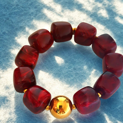 e bracelet audacieux allie modernité et raffinement grâce à ses perles en résine effet pierre, délicatement facettées, et sa perle centrale en acier inoxydable doré. Son design sculptural et lumineux en fait un bijou tendance, parfait pour illuminer vos tenues du quotidien ou vos looks d’été.

Disponible en deux teintes élégantes :

Rouge profond : une nuance vibrante et chaleureuse, symbole de passion et de vitalité.

Prune rosé : une couleur douce et féminine, qui reflète la sérénité et l’élégance.