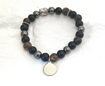 Bracelet en pierres naturelles (Onyx, Hématite, Œil du tigre) monté sur élastique, avec médaillon personnalisable. Apporte protection, ancrage et confiance en soi. Il est personnalisable avec son pendentif à graver