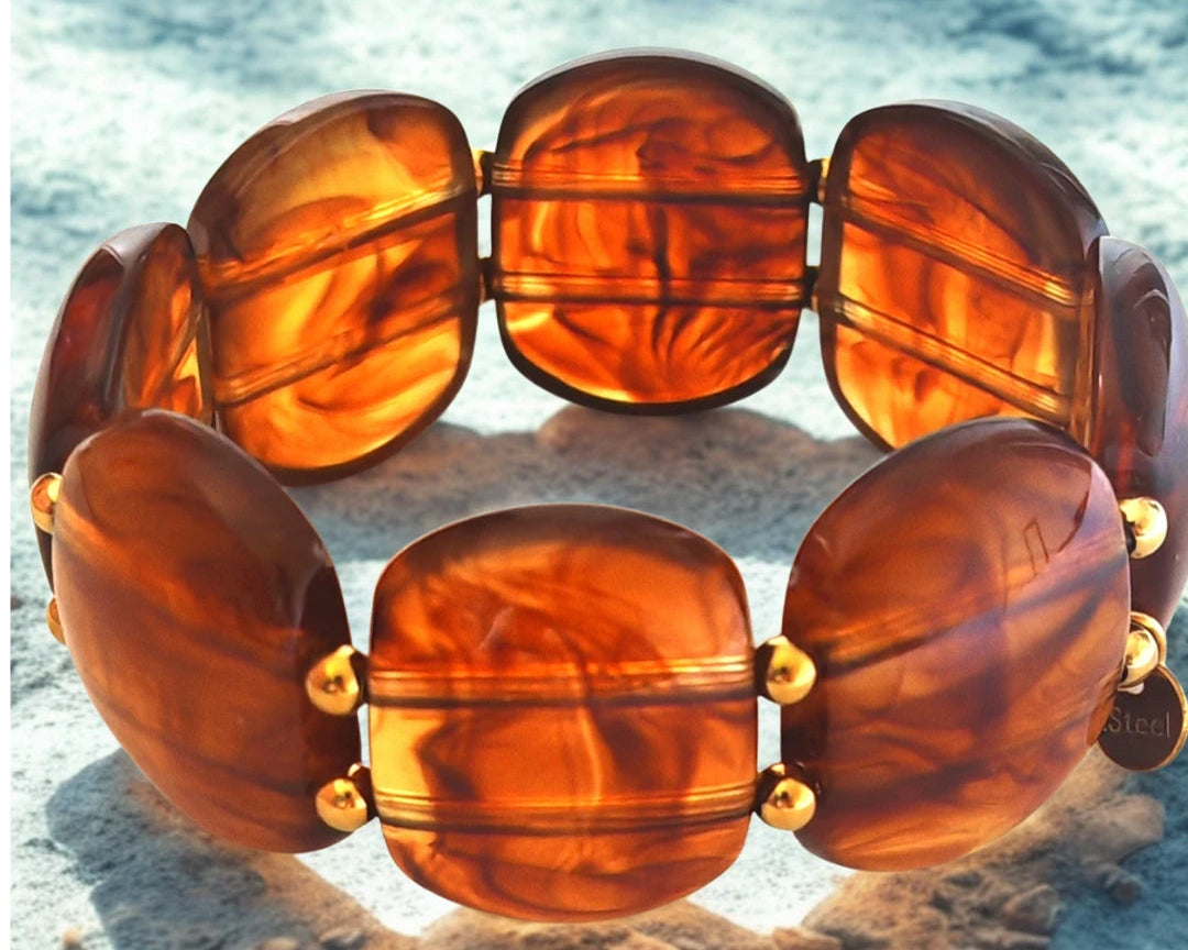 Sublimez votre poignet avec ce bracelet large en résine effet pierre naturelle, rehaussé de perles dorées en acier inoxydable. Ses reflets profonds et sa texture lumineuse en font un bijou tendance, parfait pour habiller vos tenues d’une touche chic et contemporaine.