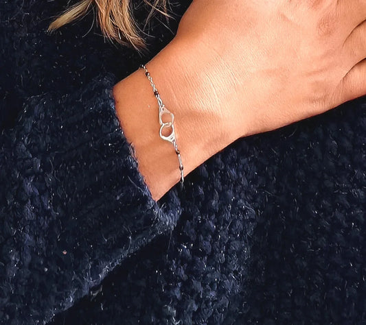 Bracelet raffiné en acier inoxydable argenté avec pendentif menottes. Résistant à l’eau et hypoallergénique, symbole de lien, de complicité et de liberté.