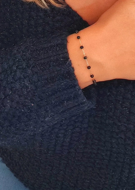 Bracelet fin en acier inoxydable doré orné de perles noires. Élégant, discret et résistant à l’eau, idéal pour un look raffiné au quotidien.