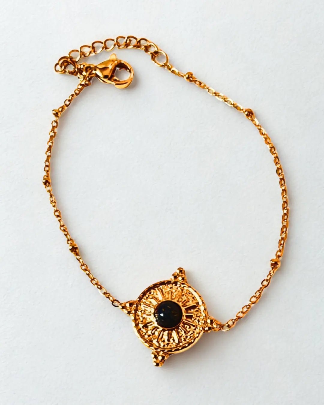 Bracelet raffiné en acier inoxydable doré orné d’un soleil et d’une pierre noire. Élégant, symbolique et résistant à l’eau, idéal à offrir ou à porter au quotidien.