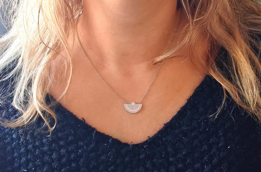 Laissez-vous séduire par l’élégance minimaliste de ce collier demi-lune en acier inoxydable argenté. Son pendentif délicatement gravé aux tons rosés évoque la douceur et l’équilibre, pour un bijou à la fois moderne et symbolique.