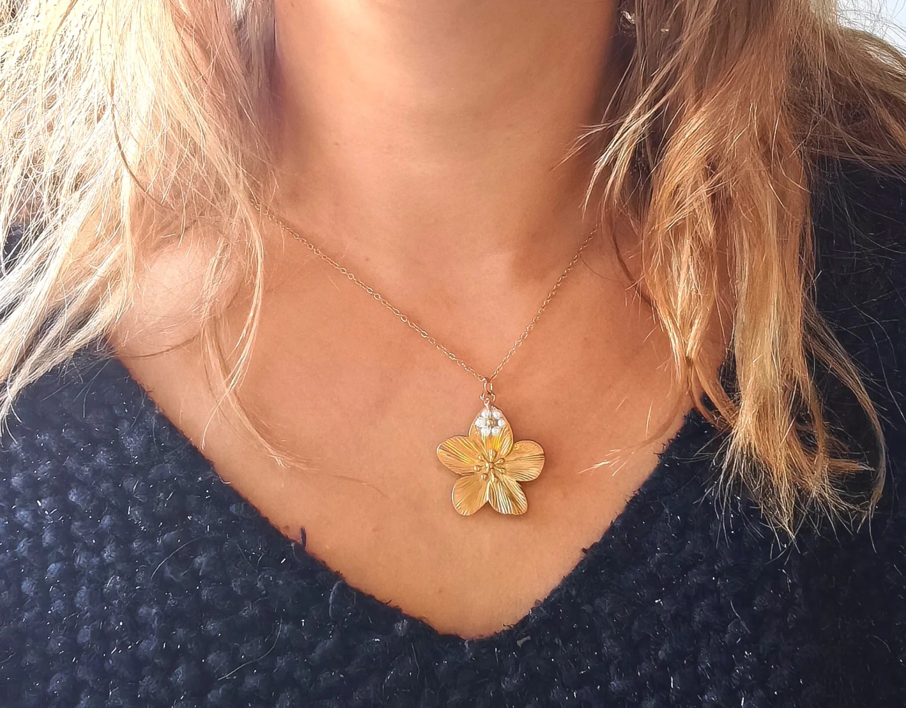 Laissez-vous séduire par la beauté de ce collier doré orné d’un pendentif en forme de fleur délicatement sculptée, rehaussée de petites perles nacrées. À la fois raffiné et lumineux, il incarne la douceur et la féminité dans toute sa splendeur.
