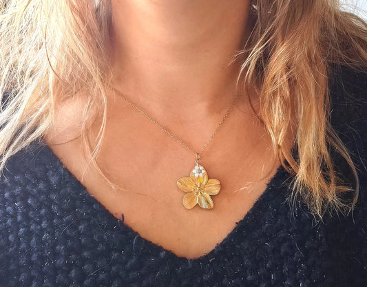 Laissez-vous séduire par la beauté de ce collier doré orné d’un pendentif en forme de fleur délicatement sculptée, rehaussée de petites perles nacrées. À la fois raffiné et lumineux, il incarne la douceur et la féminité dans toute sa splendeur.