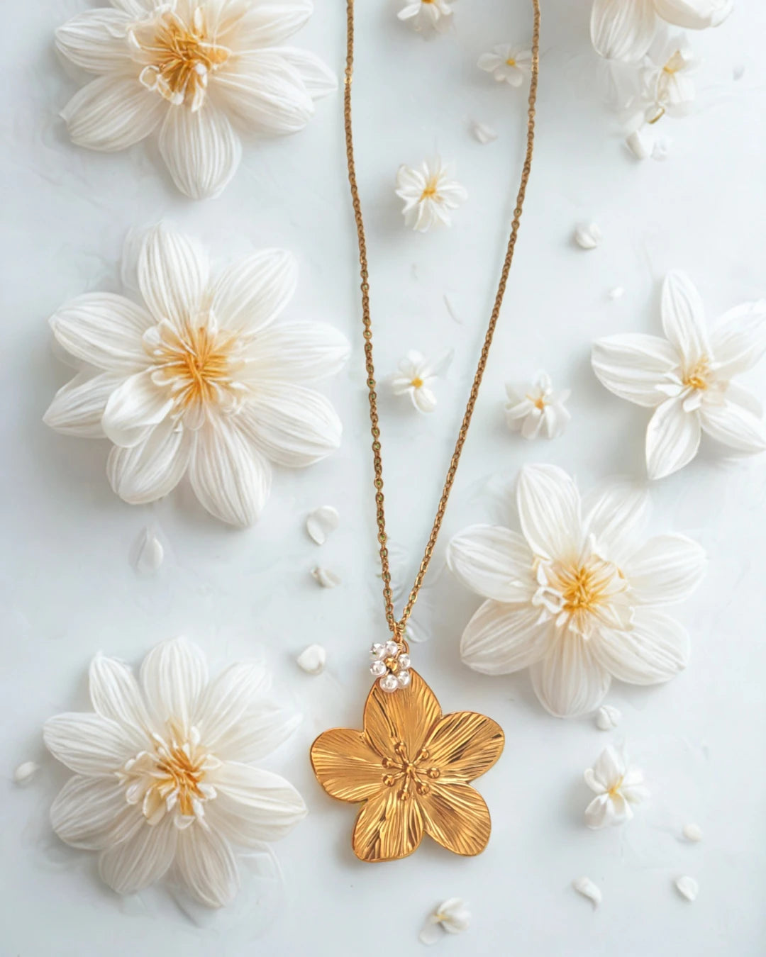 Laissez-vous séduire par la beauté de ce collier doré orné d’un pendentif en forme de fleur délicatement sculptée, rehaussée de petites perles nacrées. À la fois raffiné et lumineux, il incarne la douceur et la féminité dans toute sa splendeur.