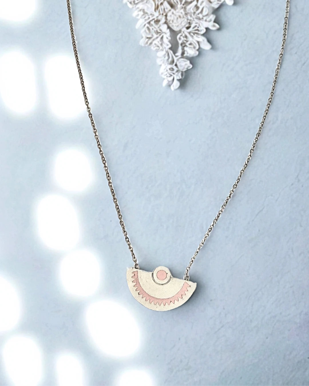 Laissez-vous séduire par l’élégance minimaliste de ce collier demi-lune en acier inoxydable argenté. Son pendentif délicatement gravé aux tons rosés évoque la douceur et l’équilibre, pour un bijou à la fois moderne et symbolique.