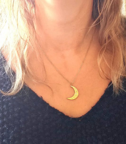 Succombez à la magie de ce collier doré orné d’un pendentif en forme de lune délicatement gravée. Symbole de féminité et de renouveau, il capte la lumière avec subtilité et apporte une touche d’éclat mystique à votre style.