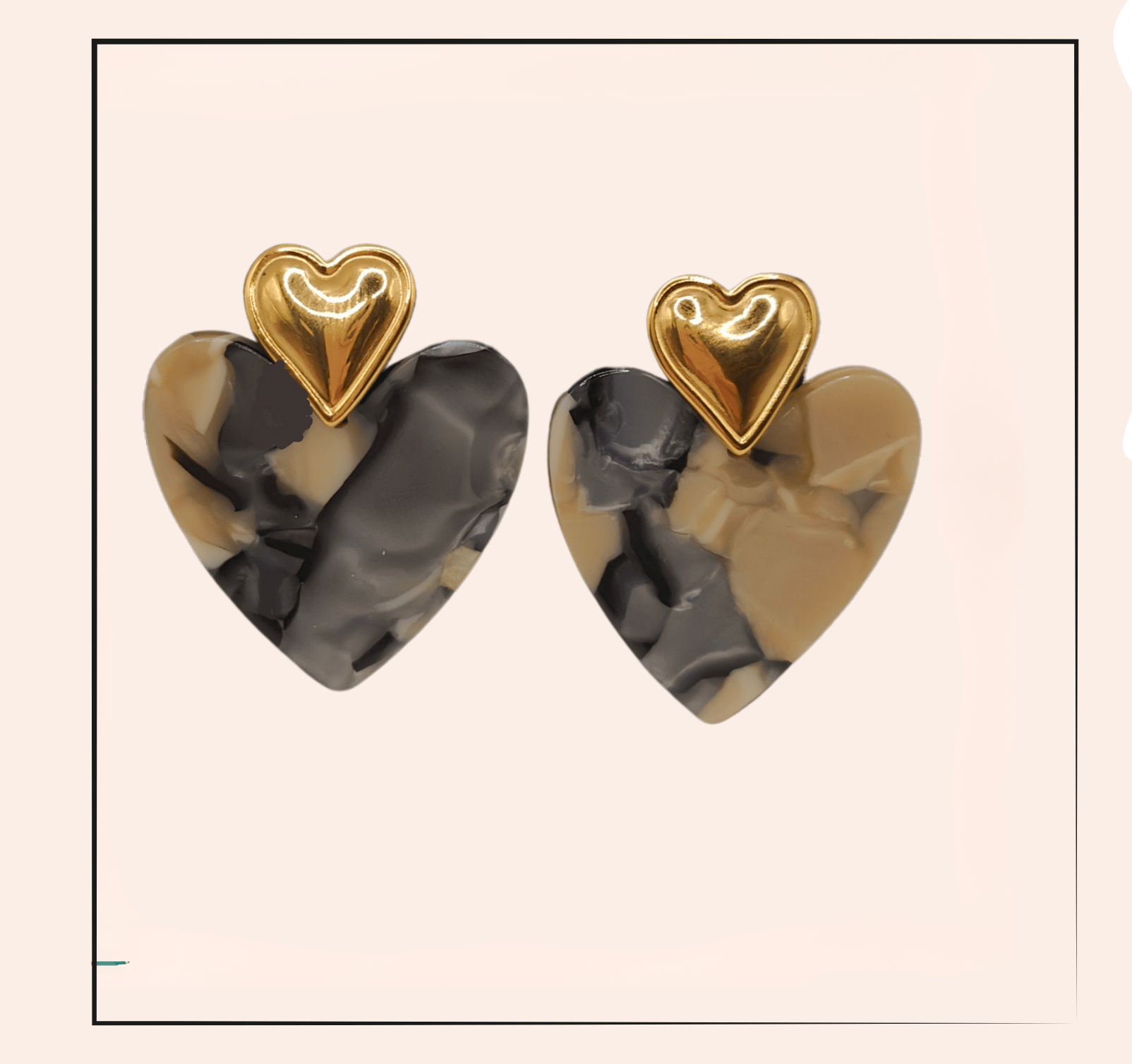 Boucle d'oreille acier inoxydable Cléa - acier inoxydable  Les boucles d'oreilles Cléa en acier inoxydable doré, en forme de cœur, allient élégance et durabilité. Leur design marbré gris et beige ajoute une touche sophistiquée, tout en étant anti-allergique