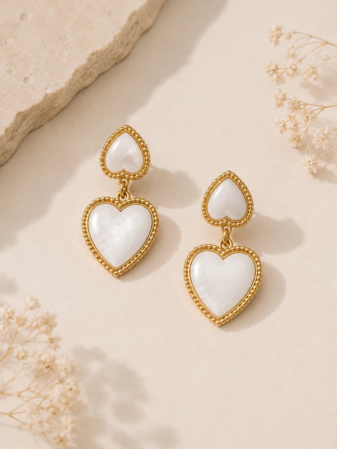Boucles d’oreilles cœur blanc nacré et doré portées par une femme