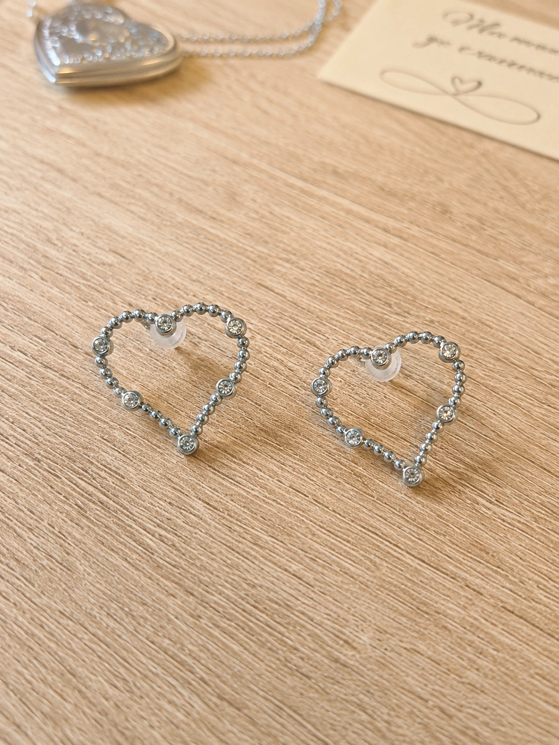 Boucles d’oreilles cœur argenté perlées portées par une femme