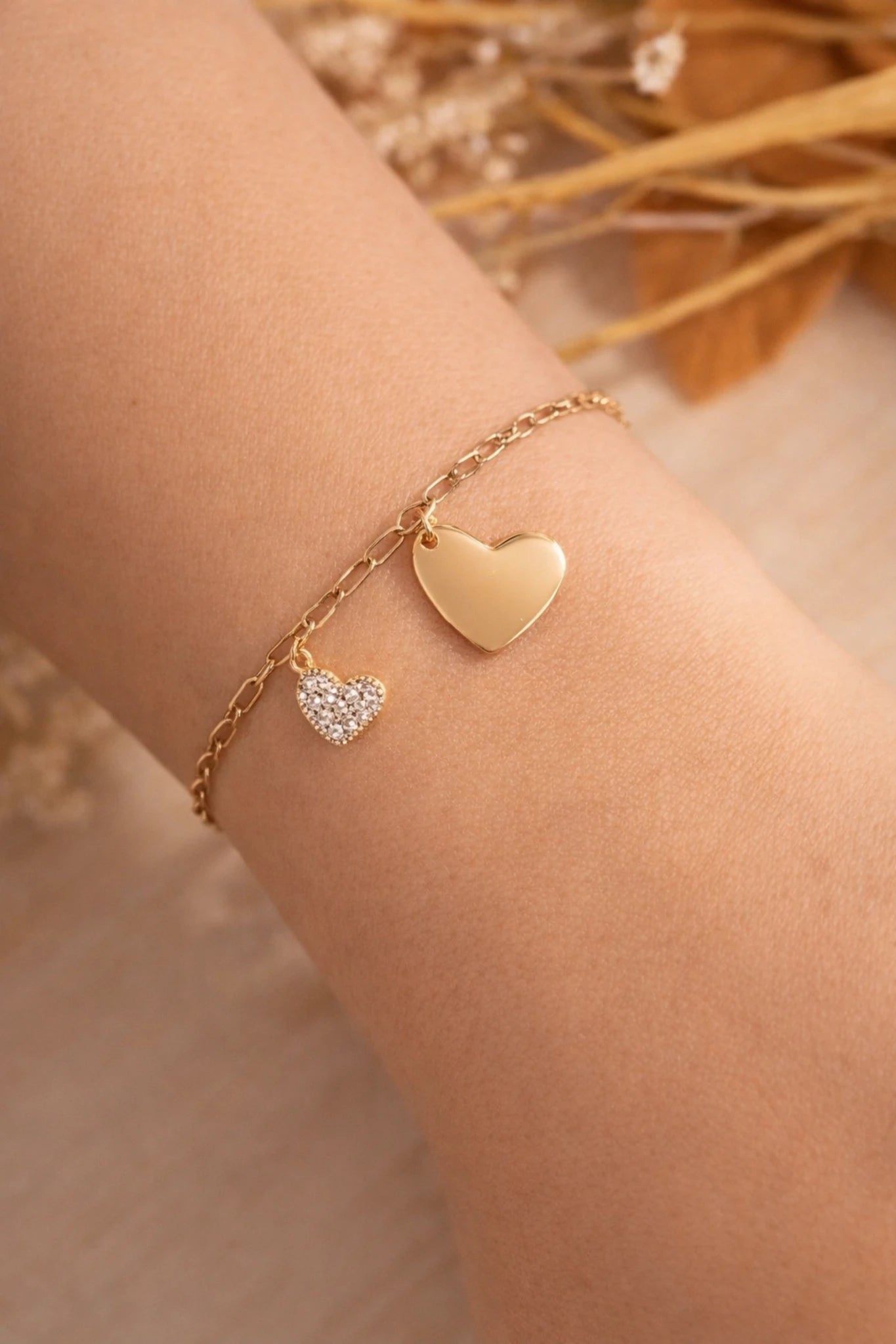 Bracelet cœur doré en acier inoxydable avec médaille personnalisable et petit cœur strass porté au poignet