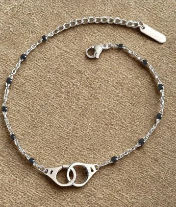 Bracelet raffiné en acier inoxydable argenté avec pendentif menottes. Résistant à l’eau et hypoallergénique, symbole de lien, de complicité et de liberté.