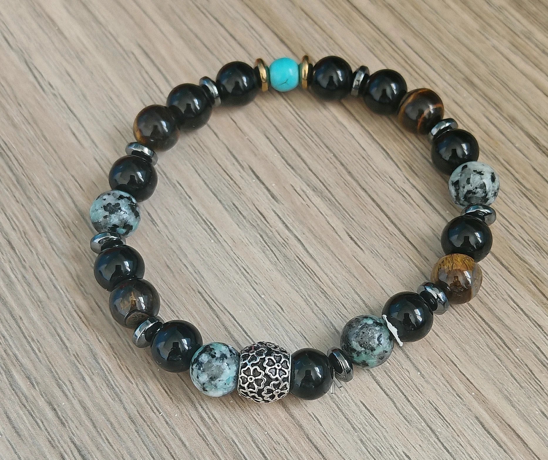 L’équilibre puissant des pierres naturelles

Chaque pierre de ce bracelet a été choisie pour sa vibration complémentaire :

L’onyx noir apaise, stabilise les émotions et renforce l’ancrage.

L’hématite agit comme un miroir protecteur contre les ondes négatives.

L’œil de tigre repousse les énergies toxiques tout en favorisant la confiance en soi.