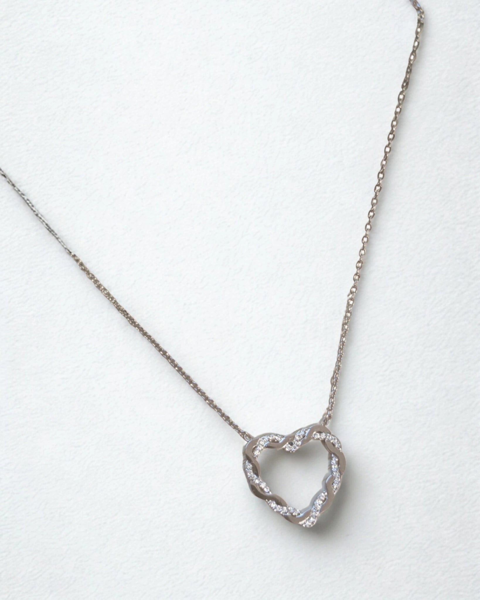 collier cœur entrelacé en acier inoxydable argent sur fond blanc