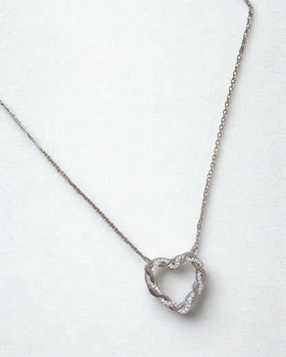 collier cœur entrelacé en acier inoxydable argent sur fond blanc