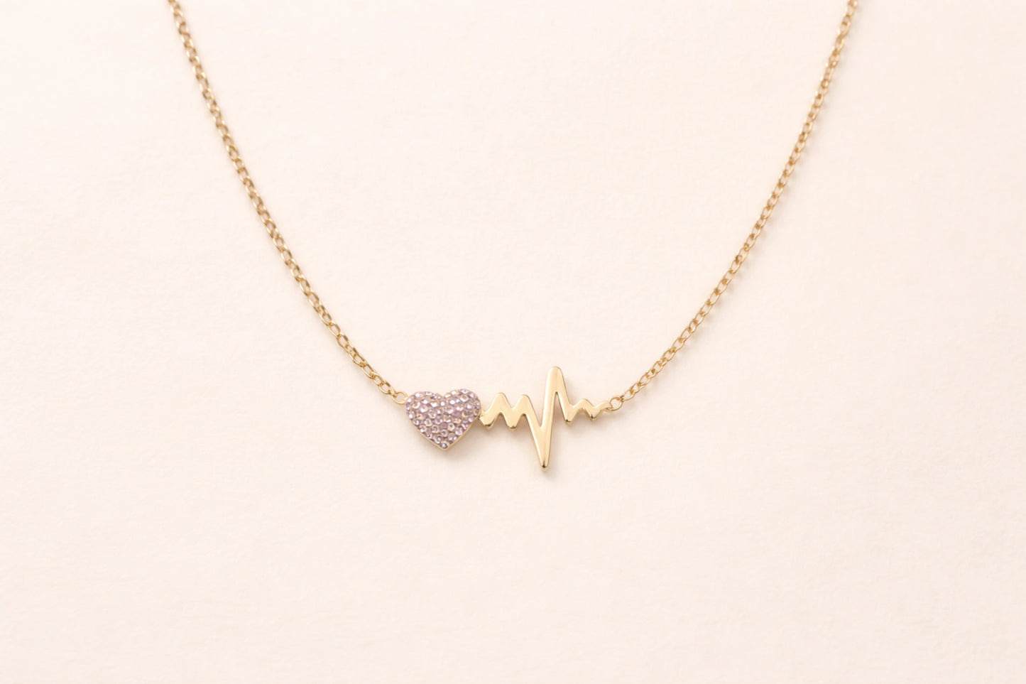 Collier cœur battement de cœur doré en acier inoxydable avec strass sur fond blanc