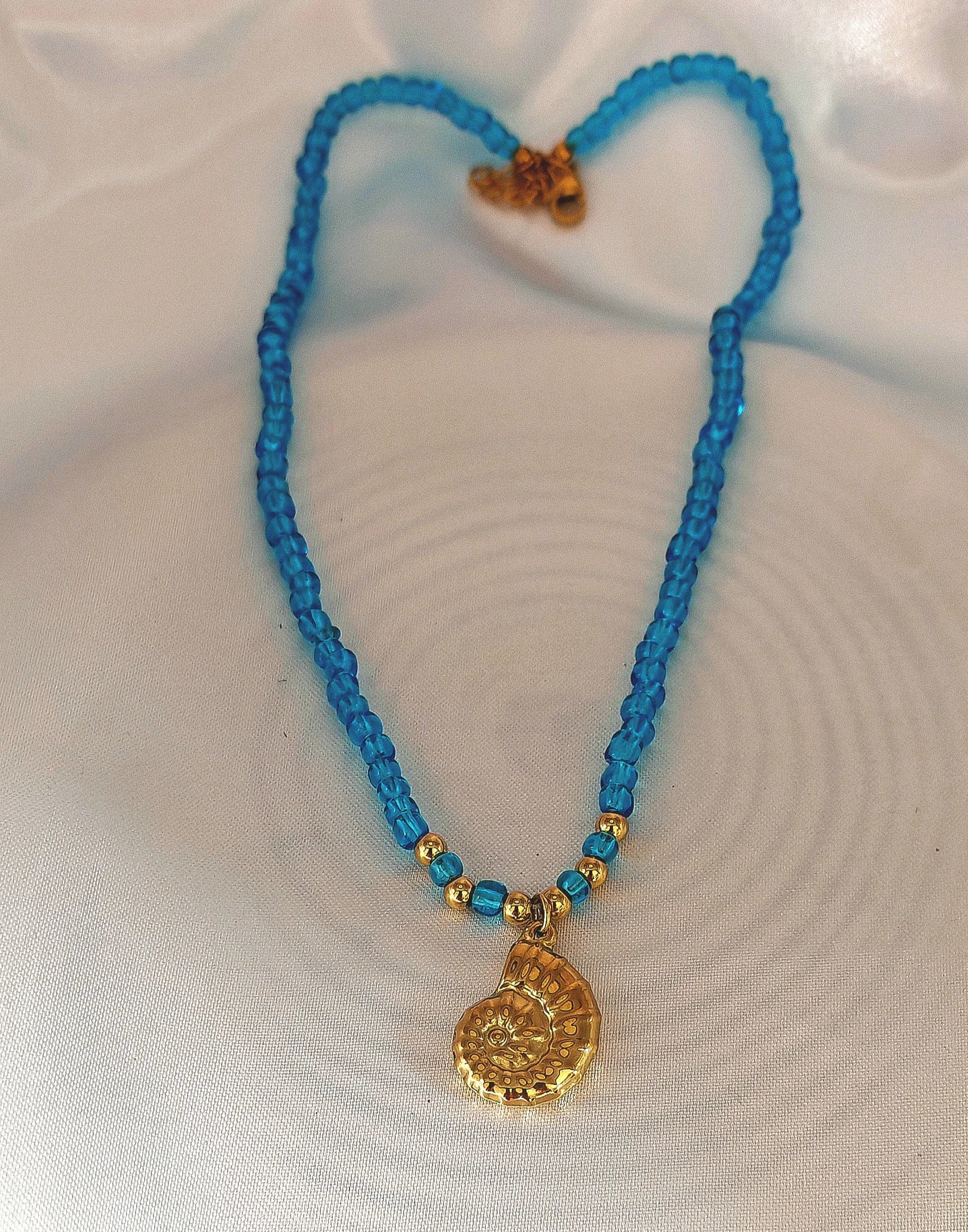 🌊 Un design élégant inspiré de l’océan
Ce collier raffiné est composé d’une chaîne en acier inoxydable ornée d’un pendentif en forme d’escargot de mer, subtilement accompagné de petites perles bleu océan qui rappellent la fraîcheur et la profondeur des lagons.

Son style marin chic s’accorde parfaitement avec une tenue estivale ou un look bohème.
Waterproof, hypoallergénique et résistant, ce bijou est conçu pour vous suivre sans s’abîmer, même sous le soleil et au bord de l’eau.