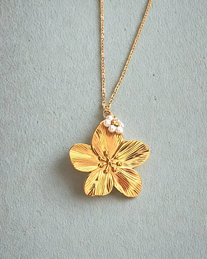 Laissez-vous séduire par la beauté de ce collier doré orné d’un pendentif en forme de fleur délicatement sculptée, rehaussée de petites perles nacrées. À la fois raffiné et lumineux, il incarne la douceur et la féminité dans toute sa splendeur.